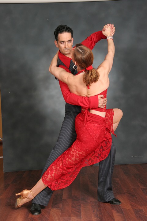 Salsa Dancing couple in red dress and grey outfit